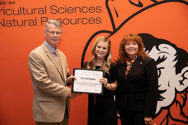 Lemoore High School's Tristan Rowell, currently an ag major at Oklahoma State University, accepts a scholarship from Dr. Tom Coon and Dr. Cynda Clary.